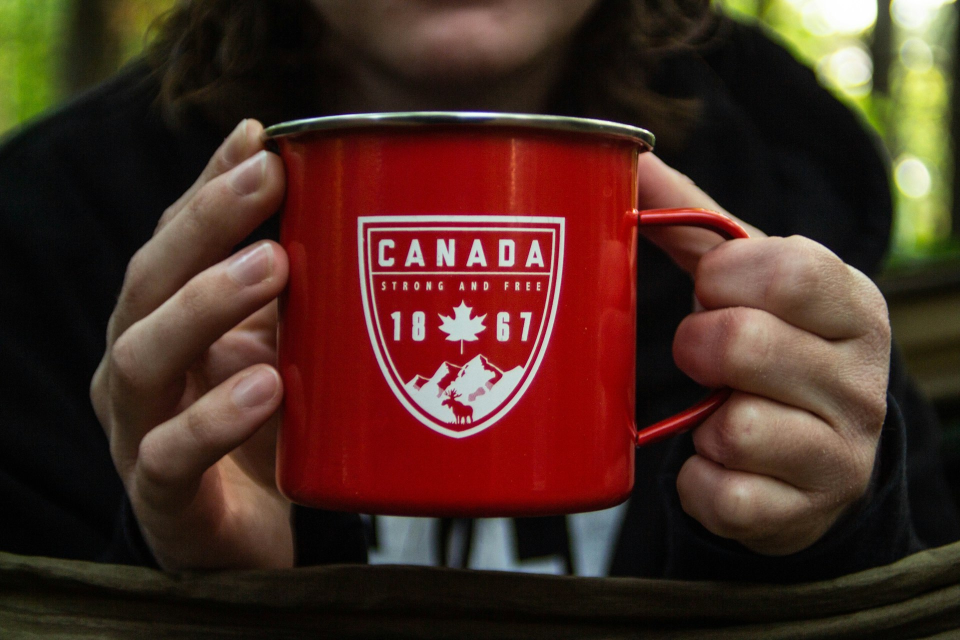 person holding red Canada flag mug